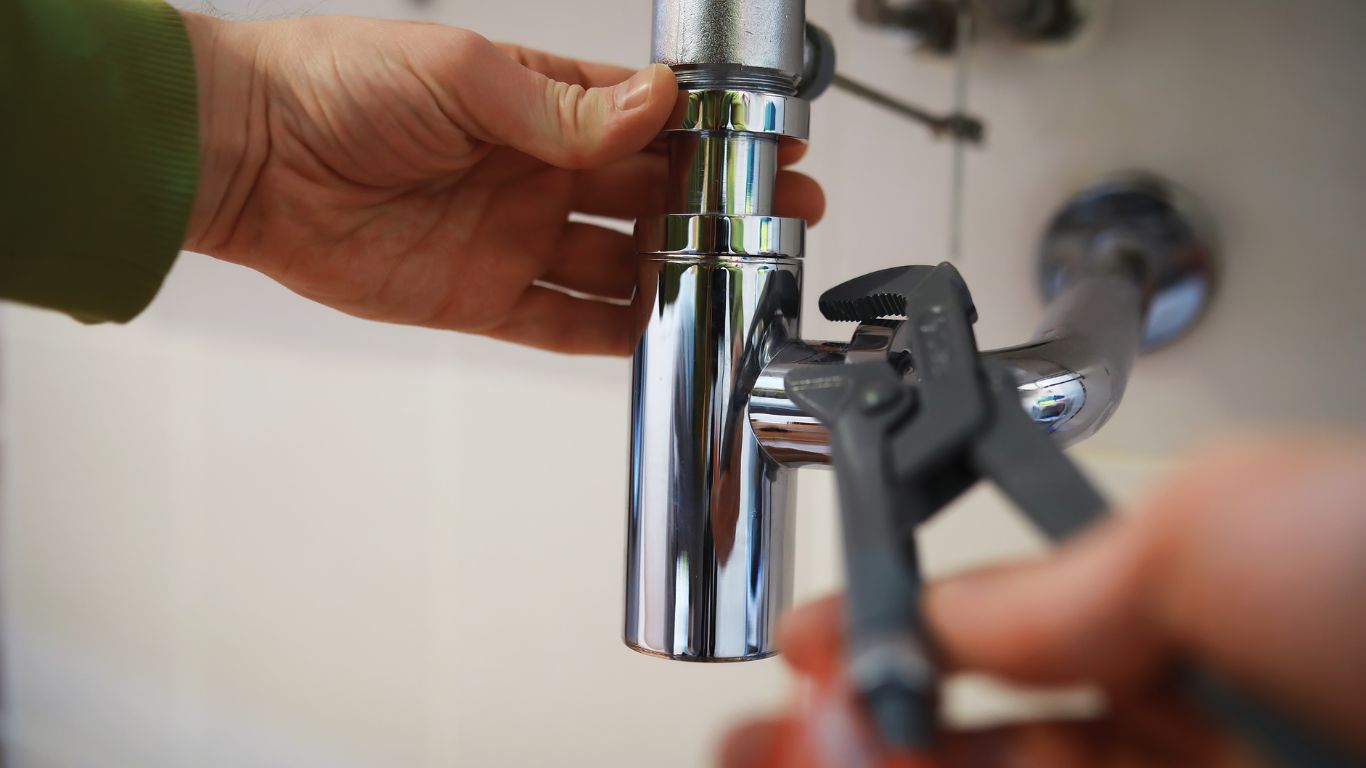 Plumbing Repair That Turns Drips into Smiles Plumber using a wrench to fix a chrome pipe during a plumbing repair.