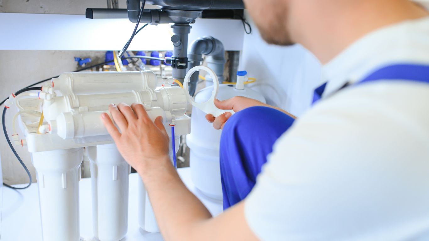 Technician installing modern water filtration systems under a kitchen sink